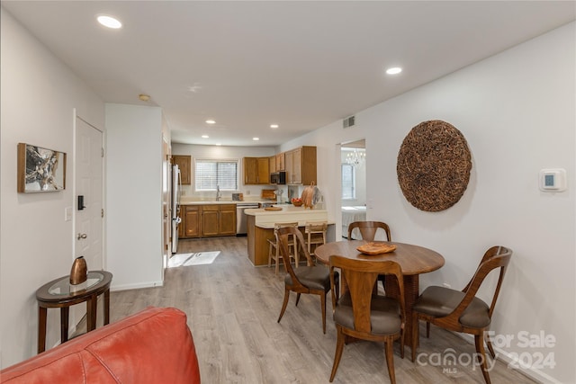 dining space featuring light wood-type flooring and sink