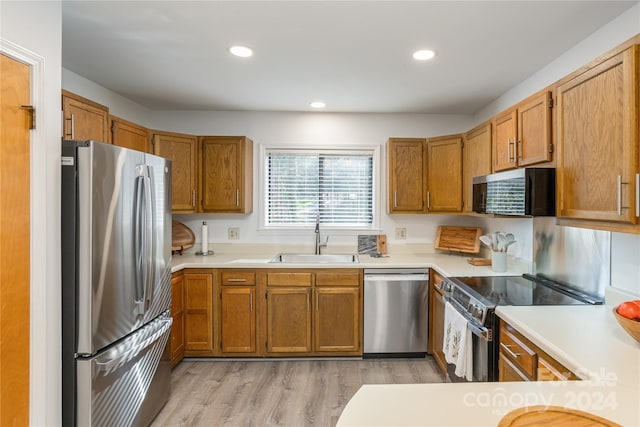 kitchen with sink, appliances with stainless steel finishes, and light hardwood / wood-style flooring