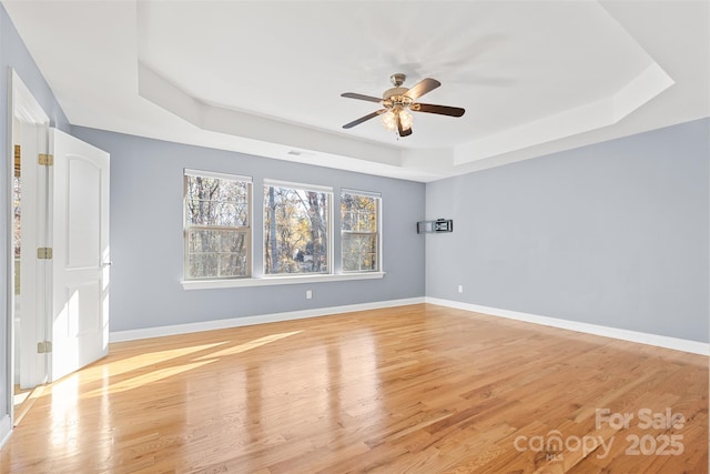 spare room featuring light hardwood / wood-style floors, a tray ceiling, and ceiling fan