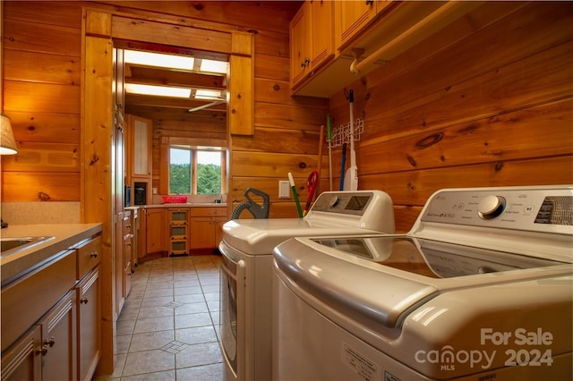 washroom featuring wooden walls, light tile patterned flooring, cabinets, and independent washer and dryer