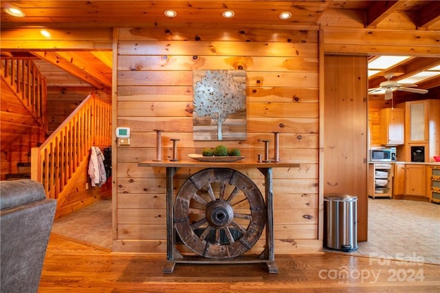 interior space with beam ceiling, wooden walls, wood-type flooring, and wooden ceiling