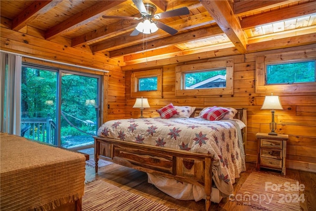 bedroom with hardwood / wood-style floors, wood walls, ceiling fan, access to exterior, and beam ceiling