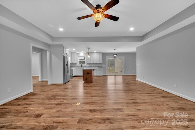 unfurnished living room featuring a sink, recessed lighting, light wood-style floors, baseboards, and ceiling fan