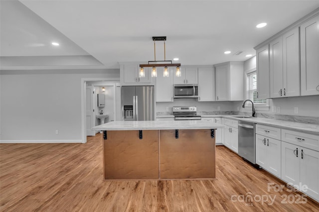 kitchen with a sink, light wood-style floors, a kitchen island, and stainless steel appliances