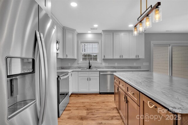 kitchen with pendant lighting, recessed lighting, light wood-style flooring, stainless steel appliances, and a sink