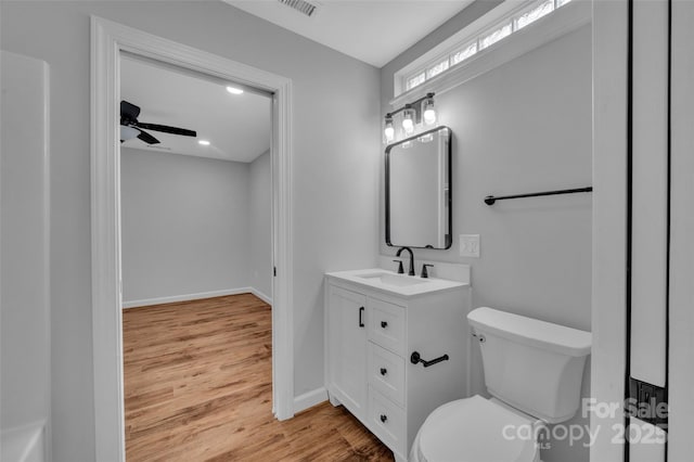 bathroom featuring toilet, wood finished floors, baseboards, ceiling fan, and vanity