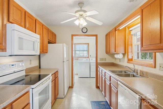 kitchen featuring washing machine and clothes dryer, a wealth of natural light, sink, and white appliances