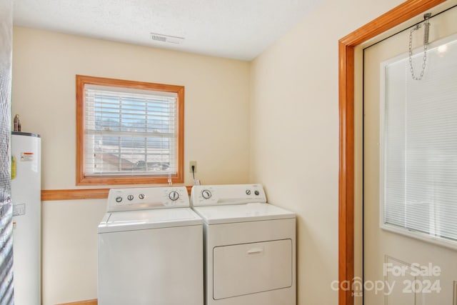 clothes washing area featuring a textured ceiling, washer and clothes dryer, and gas water heater