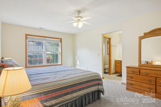 bedroom featuring ceiling fan, light colored carpet, and connected bathroom