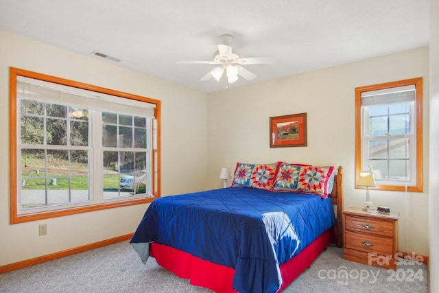 carpeted bedroom with multiple windows and ceiling fan