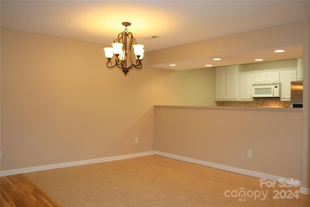 unfurnished room with an inviting chandelier