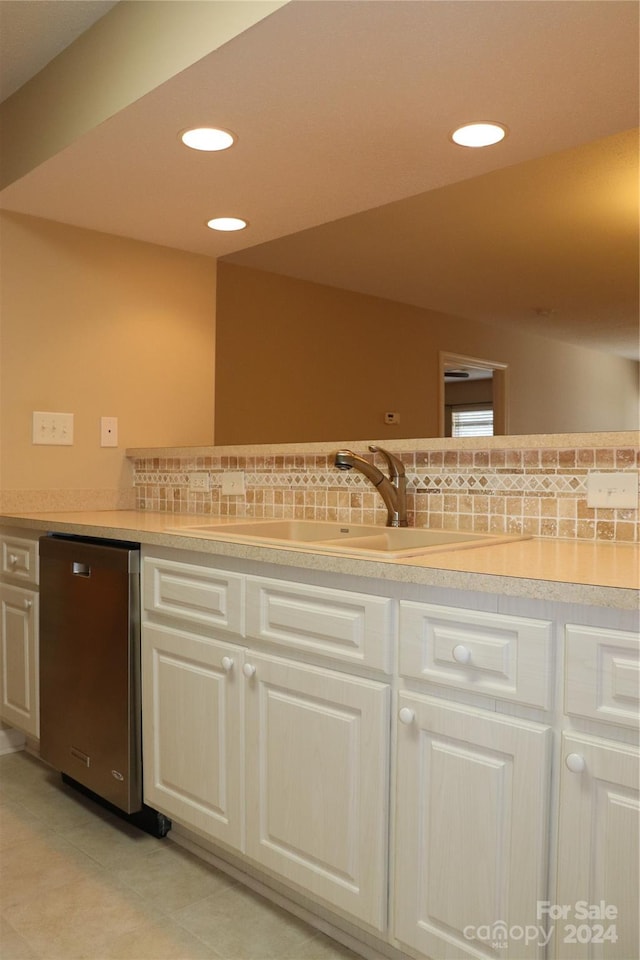 kitchen featuring dishwasher, white cabinets, sink, light tile patterned floors, and tasteful backsplash