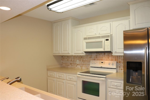 kitchen featuring white appliances, light countertops, decorative backsplash, and white cabinets