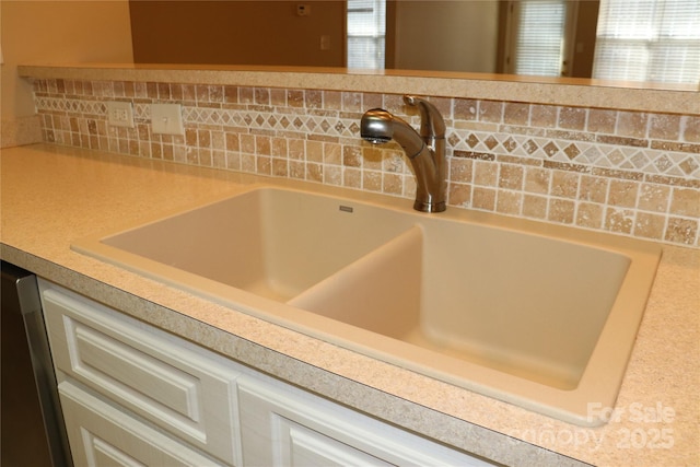 interior details featuring light countertops, a sink, and white cabinets