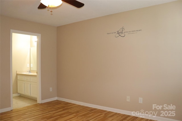 unfurnished bedroom with light wood-style flooring, baseboards, connected bathroom, ceiling fan, and a sink