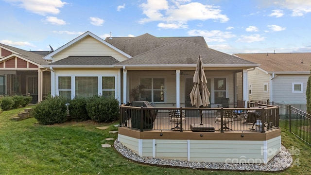 rear view of property with a lawn, a sunroom, and a wooden deck