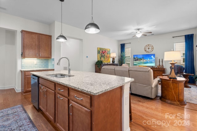 kitchen with stainless steel dishwasher, a kitchen island with sink, sink, and hardwood / wood-style flooring