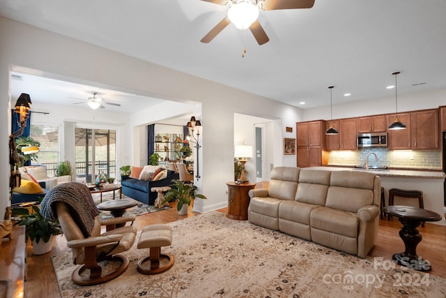 living room featuring light hardwood / wood-style floors, ceiling fan, and sink