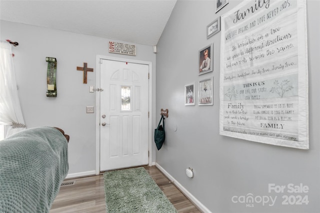 entryway with a textured ceiling, vaulted ceiling, and hardwood / wood-style flooring