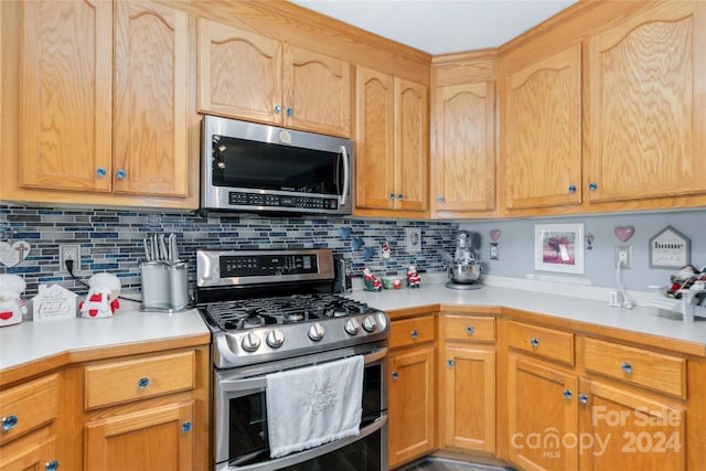 kitchen with decorative backsplash, light brown cabinets, and stainless steel appliances