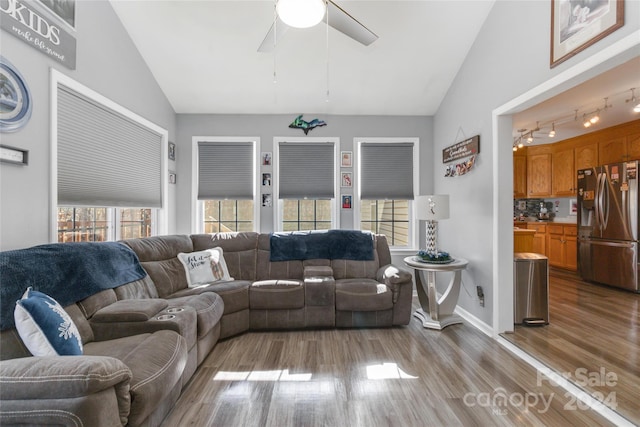 living room with ceiling fan, track lighting, vaulted ceiling, and light wood-type flooring