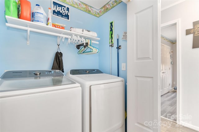 clothes washing area with washing machine and dryer and light wood-type flooring