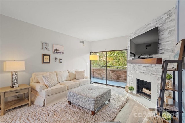 living room featuring light hardwood / wood-style flooring and a stone fireplace