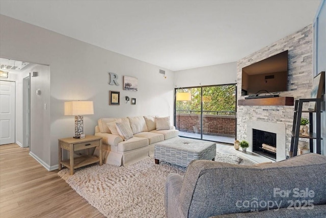 living room with hardwood / wood-style flooring and a stone fireplace