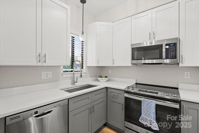 kitchen with pendant lighting, gray cabinetry, sink, white cabinetry, and stainless steel appliances