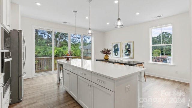 kitchen featuring pendant lighting, light hardwood / wood-style floors, white cabinetry, and plenty of natural light