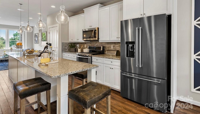 kitchen featuring a kitchen breakfast bar, white cabinets, an island with sink, and stainless steel appliances