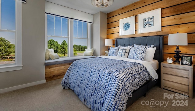 bedroom featuring carpet, multiple windows, and wood walls