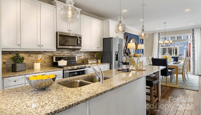 kitchen with white cabinetry, hanging light fixtures, dark hardwood / wood-style floors, crown molding, and appliances with stainless steel finishes