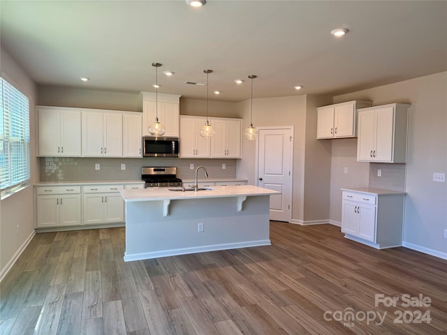 kitchen featuring white cabinets, appliances with stainless steel finishes, light hardwood / wood-style flooring, and pendant lighting