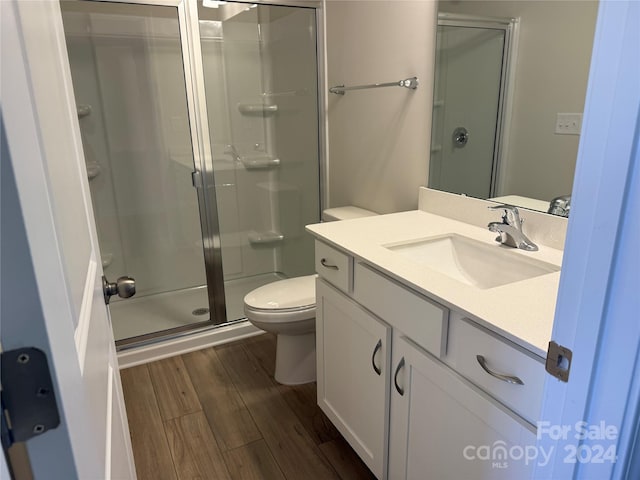 bathroom featuring hardwood / wood-style flooring, vanity, toilet, and a shower with door