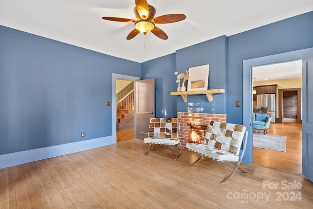 sitting room featuring ceiling fan, light hardwood / wood-style floors, and a fireplace