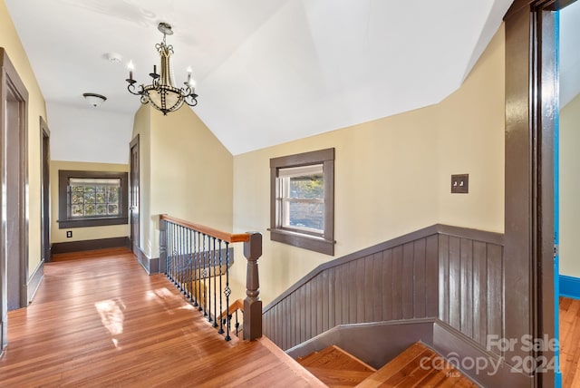 stairway featuring a notable chandelier, lofted ceiling, and wood-type flooring