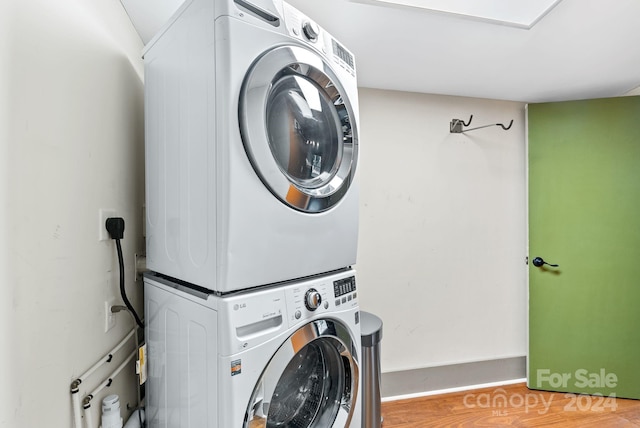 clothes washing area featuring hardwood / wood-style flooring and stacked washer / drying machine