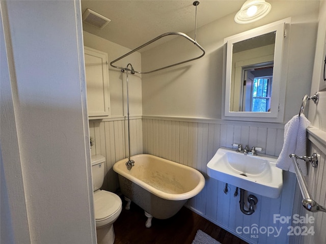 bathroom featuring a tub, sink, hardwood / wood-style floors, and toilet