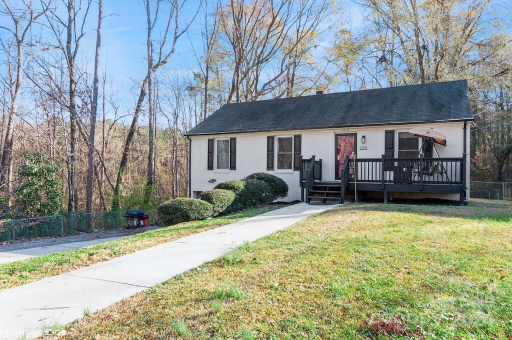 ranch-style house with a deck and a front lawn