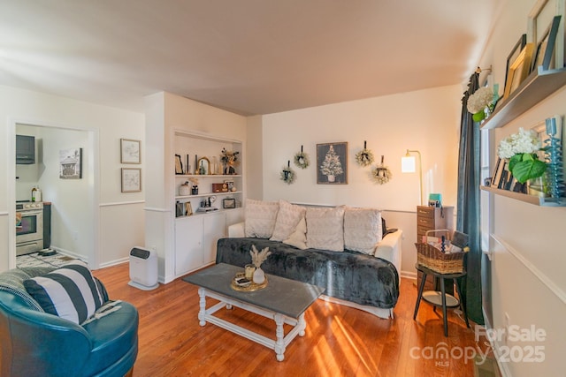 living room with built in features and light wood-type flooring