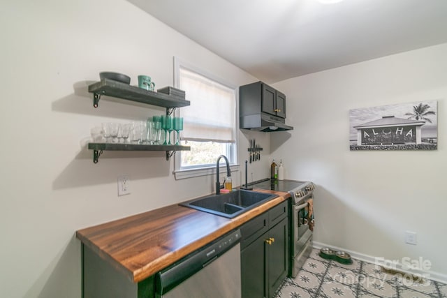 kitchen with sink, green cabinets, butcher block counters, and appliances with stainless steel finishes