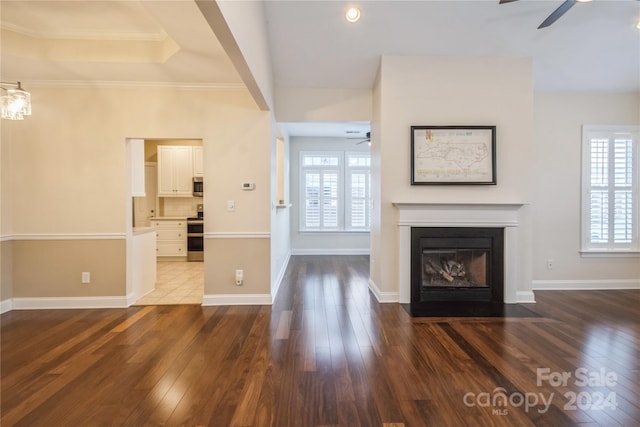 unfurnished living room featuring ornamental molding, dark hardwood / wood-style flooring, ceiling fan, and a healthy amount of sunlight