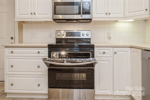 kitchen with decorative backsplash, white cabinetry, light tile patterned floors, and appliances with stainless steel finishes