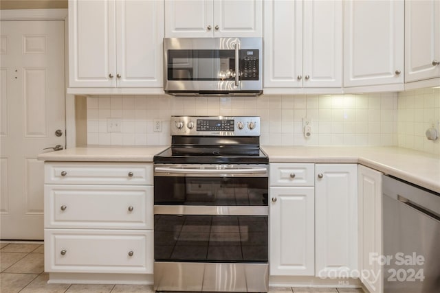 kitchen featuring white cabinets, decorative backsplash, light tile patterned floors, and stainless steel appliances