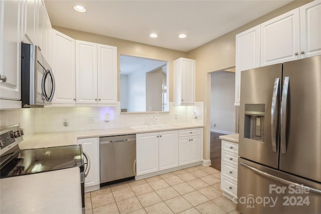 kitchen featuring white cabinets, sink, appliances with stainless steel finishes, tasteful backsplash, and light tile patterned flooring