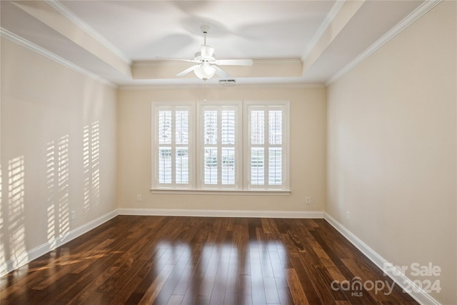 empty room with a raised ceiling, crown molding, ceiling fan, and dark wood-type flooring