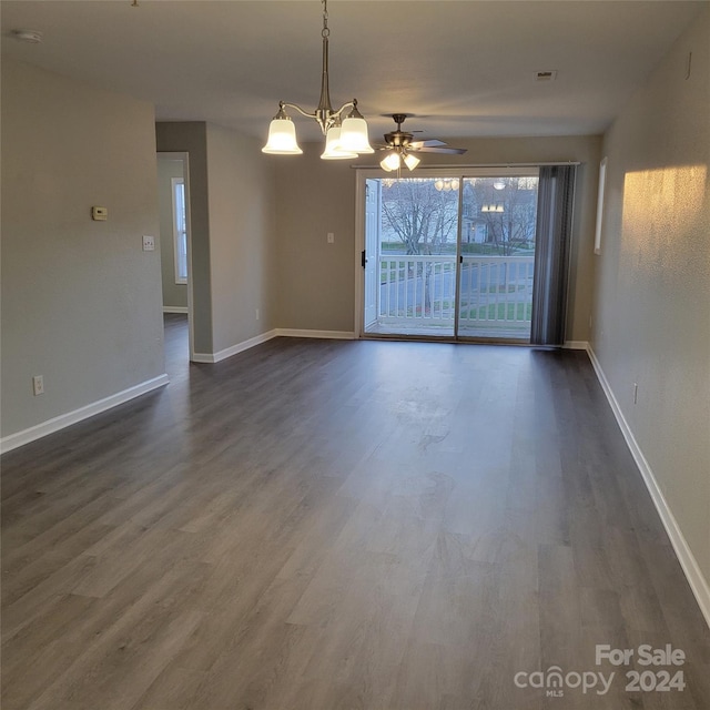 spare room featuring ceiling fan with notable chandelier and dark hardwood / wood-style floors