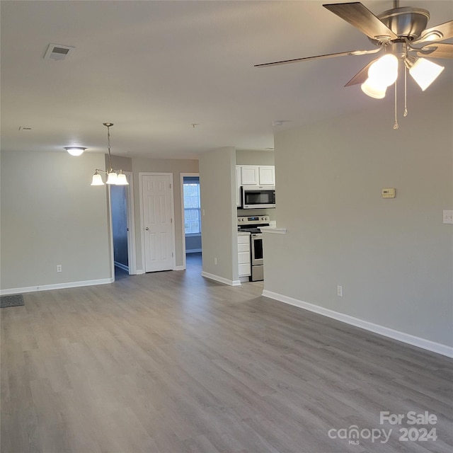 unfurnished living room featuring ceiling fan with notable chandelier and light wood-type flooring