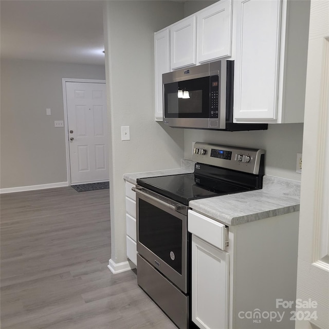 kitchen with white cabinets, stainless steel appliances, and light hardwood / wood-style flooring